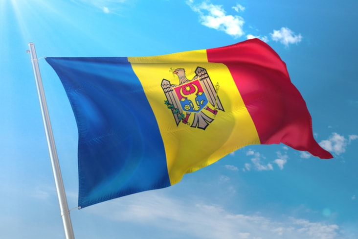 The flag of Moldova flies against a blue sky