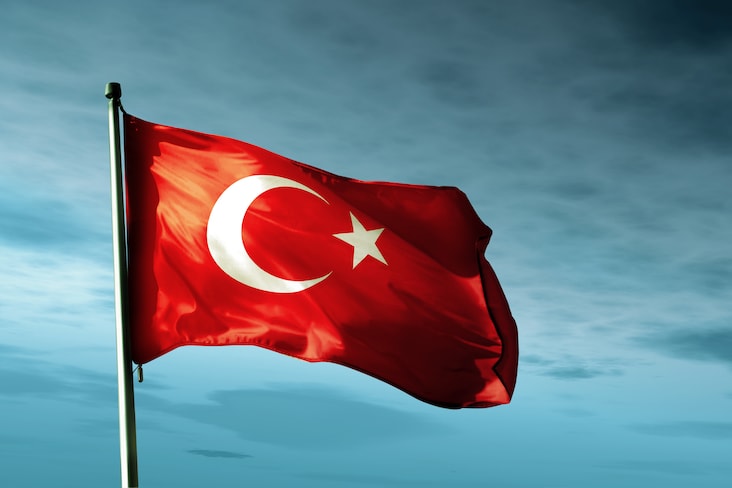 Türkiye's flag flying against a dark blue sky