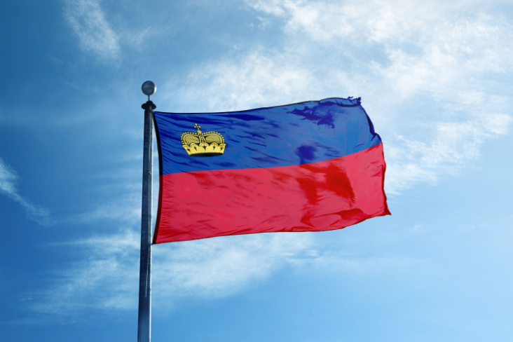 Liechtenstein's flag flying in the wind with a blue sky