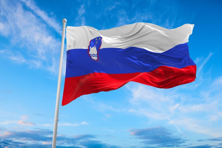 Slovenia's flag flying with a blue sky behind